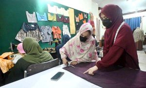 A tailoring instructor guides a trainee during a garment stitching class at Fixit Skill Centre. 
