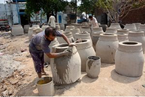 Skilled potters shape traditional clay tandoors by hand, preserving age-old craftsmanship at their workplace.