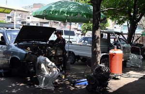 A young mechanic repairing a car engine at a roadside workshop near Pirwadhai area in the city