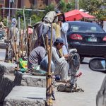 Daily-wage laborers sit along a roadside with their specialized tools, including jackhammers and picks, as they wait for potential employers to offer construction or renovation work at Tarlai area