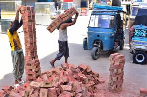 Workers carry bricks during house construction on a hot day in the city.