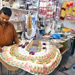 A worker prepares a traditional currency-note garland used in wedding ceremonies at his shop in a local market