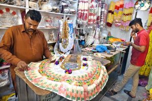 A worker prepares a traditional currency-note garland used in wedding ceremonies at his shop in a local market