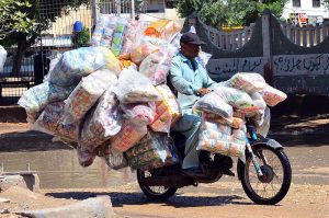 A motorcyclist rides through stagnant rainwater after rainfall while carrying bags of chips on his way in Latifabad