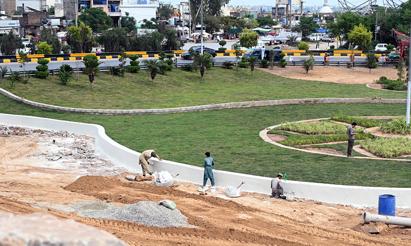 Laborers busy in beautification work at Koral Chowk Interchange on the Expressway in the Federal Capital