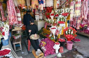 Vendors craft and display colorful flower garlands to attract customers at their roadside shops in the city.