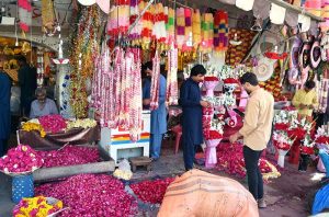Vendors craft and display colorful flower garlands to attract customers at their roadside shops in the city.