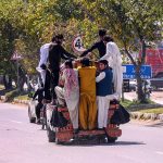 People travel dangerously while hanging from a Suzuki van on Lehtrar Road, prompting the need for the concerned authorities to take notice