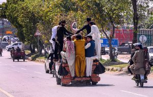 People travel dangerously while hanging from a Suzuki van on Lehtrar Road, prompting the need for the concerned authorities to take notice