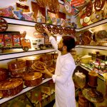 Youngster craftsman selling and displaying hand made wooden decoration pieces to attract the customer here at Namaz mandi Chowk