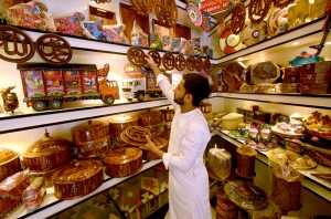 Youngster craftsman selling and displaying hand made wooden decoration pieces to attract the customer here at Namaz mandi Chowk