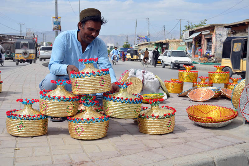A vendor decorates traditional handwoven Patari baskets with colorful beads and ribbons, highlighting Balochistan’s rich craft heritage and the enduring skill of local artisans