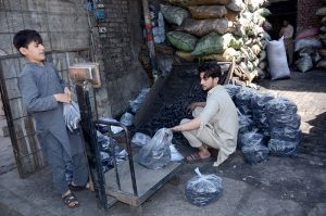 Workers weigh coal after packing it into plastic bags at a local depot.