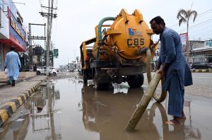 A Cantonment Board worker removes rainwater from College Road using a suction pump