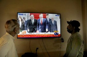 People watch television news coverage of the U.S.–Iran peace talks in Islamabad as diplomatic efforts continue in the capital amid heightened global attention