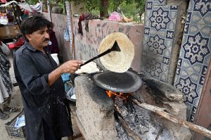 A vendor bakes fresh bread for customers at his roadside hotel in the city.