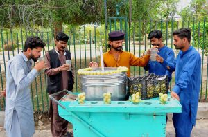 A roadside vendor prepares and serves fresh lemonade to customers at a stall, as people gather to enjoy the refreshing drink in the city.