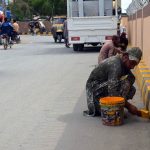 Workers are painting and marking the road divider on a newly constructed roadway linking Chaman Phatak to Koila Phatak, helping organize traffic flow and improve road safety