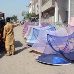 A vendor displays and sells mosquito nets to attract customers at a roadside setup