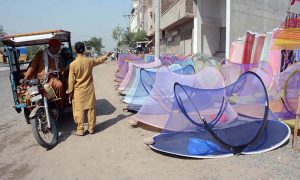 A vendor displays and sells mosquito nets to attract customers at a roadside setup