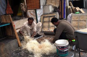 Workers are preparing and filling side brackets with wood wool for room air coolers due to increased demand amid rising temperatures, as the country observe International Labour Day.