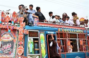 Passengers travel on the rooftop of a bus on Larkana-Kambar Road, risking their lives and calling for urgent attention from authorities.