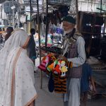 An elderly vendor sells handmade woolen toys to woman