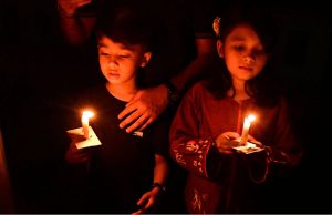 Members of the Christian community take part in their religious rituals, holding candles during the Easter prayer at St. Francis Xavier Catholic Church.