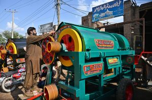 Worker busy in making thrasher machine at his work place.