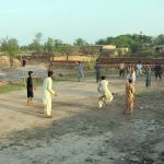 A group of youngsters playing a friendly volleyball match at an open ground in a village area