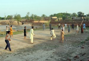 A group of youngsters playing a friendly volleyball match at an open ground in a village area