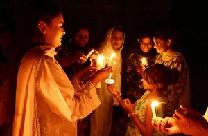 Members of the Christian community take part in their religious rituals, holding candles during the Easter prayer at St. Francis Xavier Catholic Church.