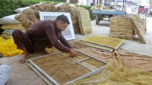 A worker busy preparing ‘khas’ for room-cooler at his workplace