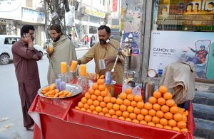 A vendor making orange juice for customers at Double Road.