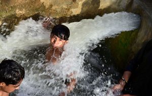 Youngsters dive into a tubewell poll to swim and bathe to beat the heat at Hala Naka.