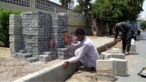 Labourers are busy installing durable tiles on a footpath as part of a city beautification and road construction project, with multiple road works currently underway across the area