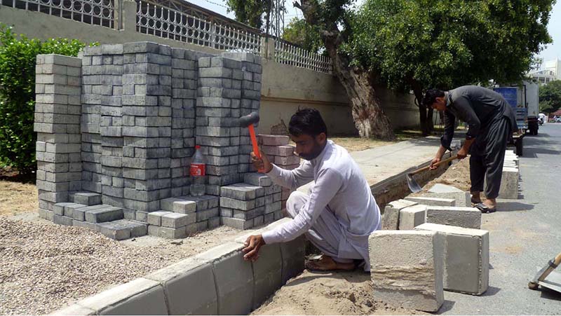 Labourers are busy installing durable tiles on a footpath as part of a city beautification and road construction project, with multiple road works currently underway across the area