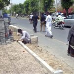 Labourers are busy fixing cemented blocks at roadside