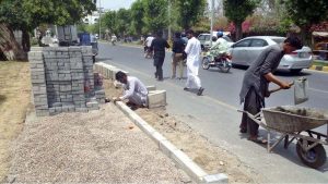 Labourers are busy fixing cemented blocks at roadside