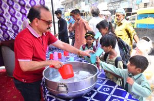 A volunteer offers cool drinking water to children at a heatstroke relief camp organized by the district administration at Hyder Chowk amid scorching heat.