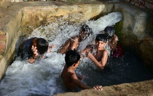 Youngsters dive into a tubewell poll to swim and bathe to beat the heat at Hala Naka.