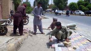 Labourers are busy installing durable tiles on a footpath as part of a city beautification and road construction project, with multiple road works currently underway across the area