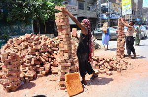 Labourers arrange piles of bricks into neat columns during the construction of a house.