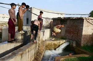 Youngsters dive into a tubewell poll to swim and bathe to beat the heat at Hala Naka.