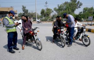 Traffic police wardens issue challans to motorcyclists without helmets during enforcement drive on Grand Trunk Road to ensure road safety compliance.