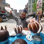 A vendor showers water on coconut to keep it fresh and attract the customers at Namak Mandi Chowk