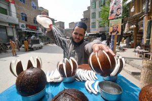 A vendor showers water on coconut to keep it fresh and attract the customers at Namak Mandi Chowk