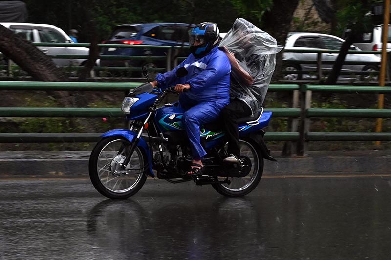 Motorcyclist covered himself with a plastic sheet to protect from rain that experienced in the Provincial Capital