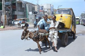 A Donkey cart holder pulling an out of order Auto rickshaw to a mechanic for repair.