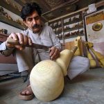 A craftsman is busy making the traditional musical instrument, Rabab, at his workshop in the Tehsil area